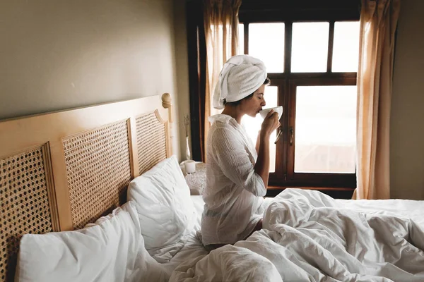 Belle jeune femme heureuse buvant du café ou au lit à l'hôtel — Photo