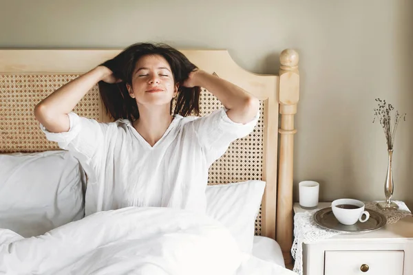 Hermosa joven feliz acostada en la cama por la mañana en el hotel —  Fotos de Stock