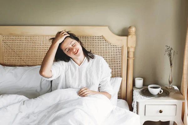 Hermosa joven feliz acostada en la cama por la mañana en el hotel —  Fotos de Stock