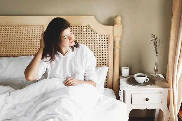 Hermosa joven feliz acostada en la cama por la mañana en el hotel —  Fotos de Stock