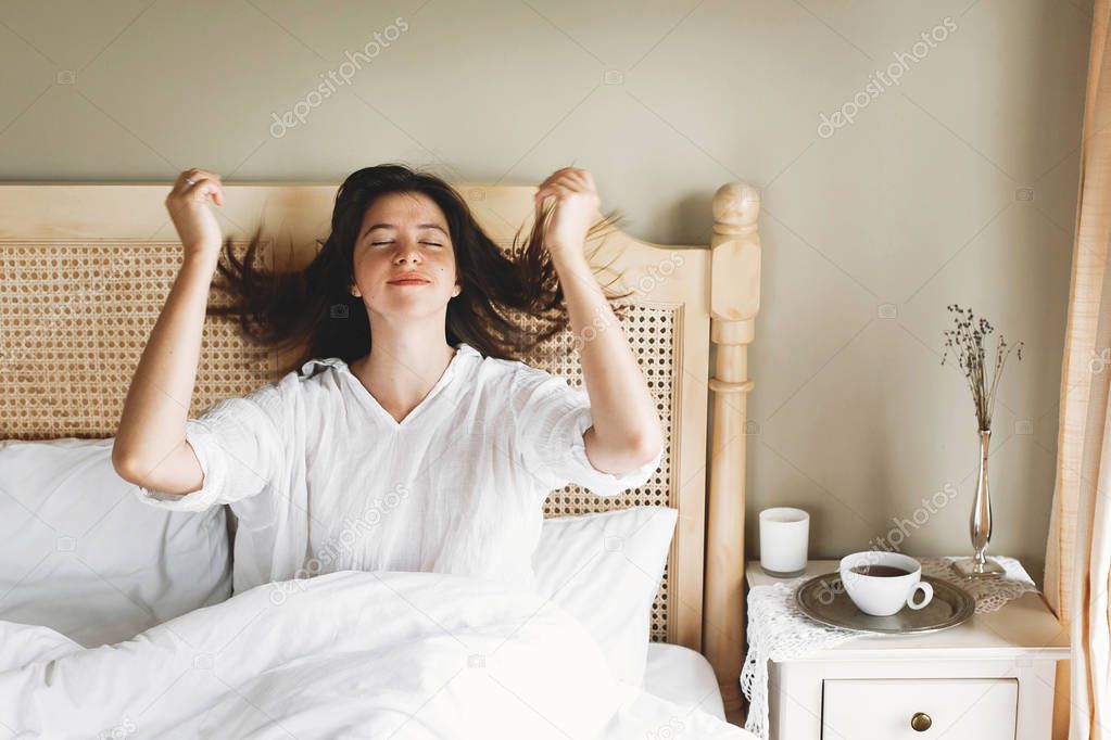 Beautiful happy young woman lying in bed in the morning in hotel