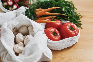 Mutfakta ahşap masada eko pamuk torbalarda taze sebze. 