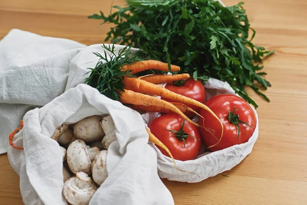Färska grönsaker i Eco bomull påsar på träbord i köket. — Stockfoto