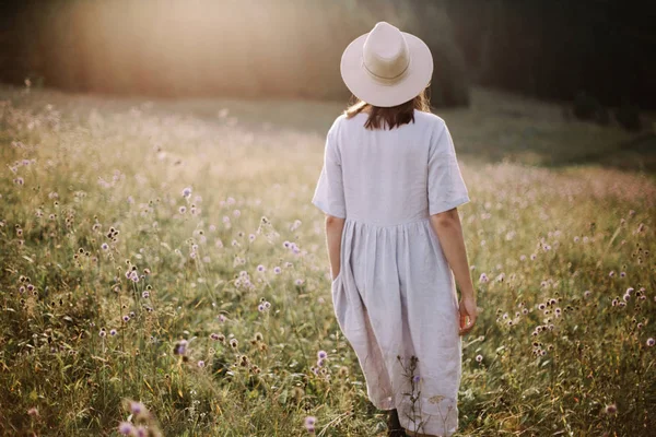 Menina elegante em vestido rústico andando em flores silvestres em mea ensolarada — Fotografia de Stock