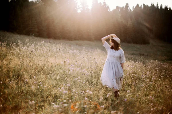 Menina elegante em vestido rústico andando em flores silvestres em mea ensolarada — Fotografia de Stock