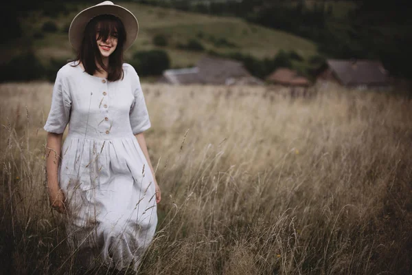 时尚的女孩在亚麻连衣裙和帽子走在草药和野生 — 图库照片