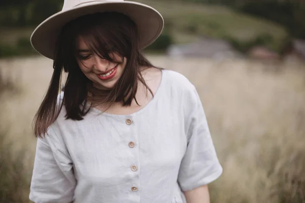 Gadis bergaya dengan gaun linen dan topi berjalan di antara tanaman herbal dan liar — Stok Foto