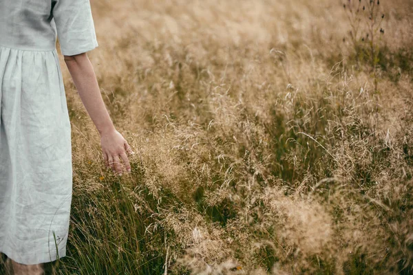 Stijlvolle meisje in linnen jurk Holding hand onder kruiden en wildflo — Stockfoto