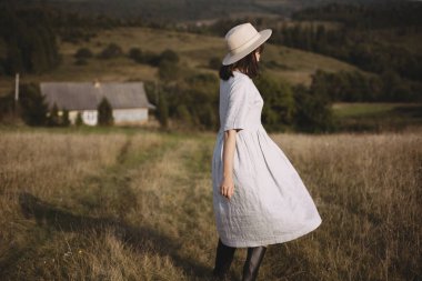 Güneşli alan çim yürüyen keten elbise ve şapka şık kız