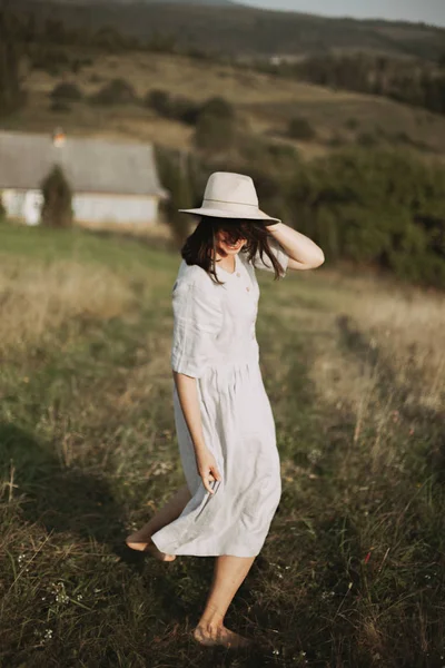 Fille élégante en robe de lin et chapeau courir pieds nus dans l'herbe dans — Photo