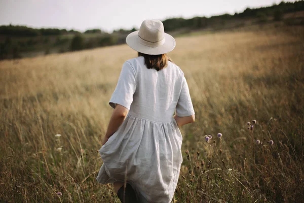 Stijlvolle meisje in linnen jurk wandelen tussen kruiden en wilde bloemen — Stockfoto