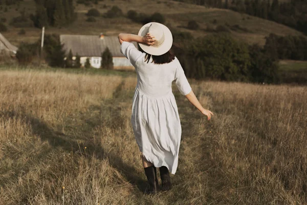 Menina elegante em vestido de linho e chapéu andando entre ervas e selvagens — Fotografia de Stock