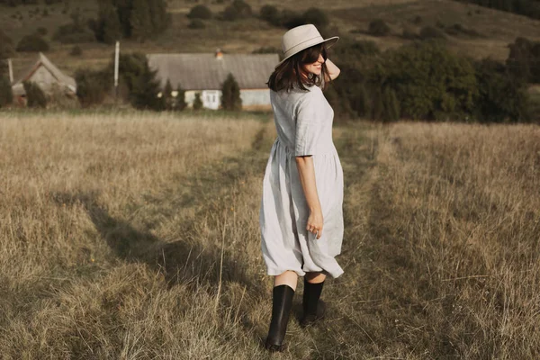 Stylish girl in linen dress and hat running and smiling in sunny — Stock Photo, Image