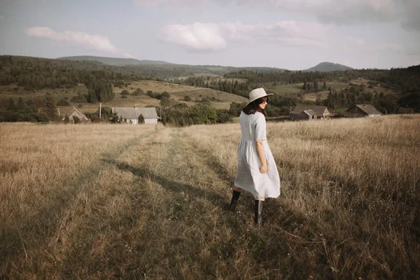 Fille élégante en robe de lin et chapeau marche parmi les herbes et sauvage — Photo