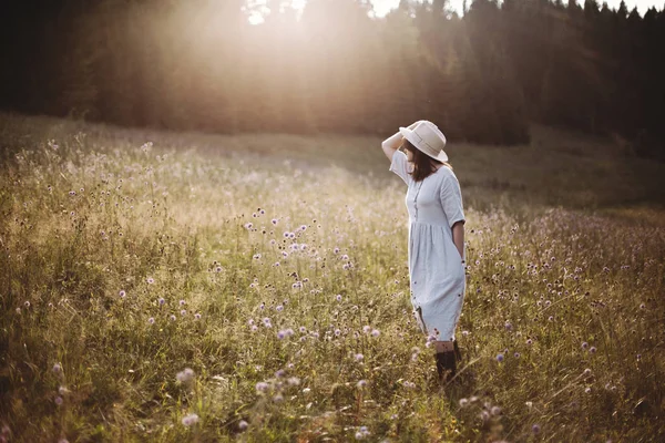 Stílusos lány rusztikus ruhában séta vadvirágok a napfényes MEA — Stock Fotó