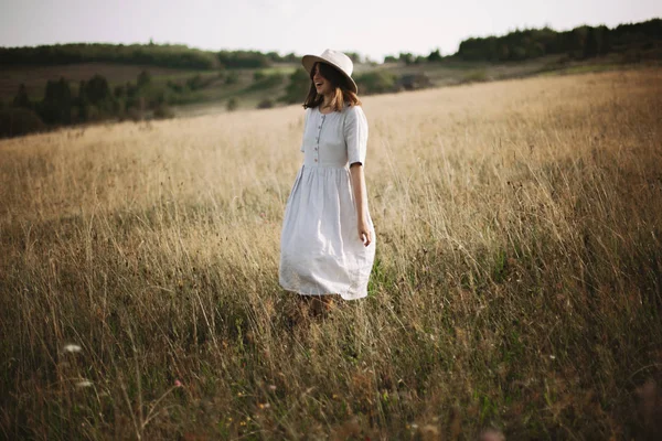 Stilvolles Mädchen im Leinenkleid, das zwischen Kräutern und Wildblumen wandelt — Stockfoto