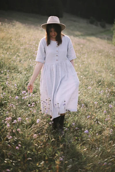 Κομψό κορίτσι σε ρουστίκ φόρεμα περπάτημα σε αγριολούλουδα στο Sunny mea — Φωτογραφία Αρχείου