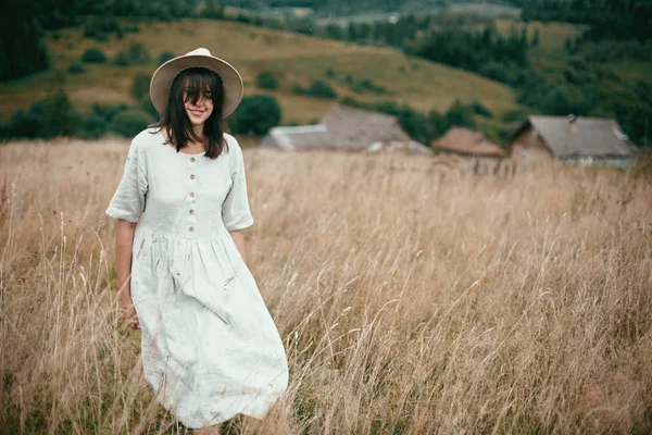 Elegante chica en vestido de lino y sombrero caminando entre hierbas y salvajes — Foto de Stock