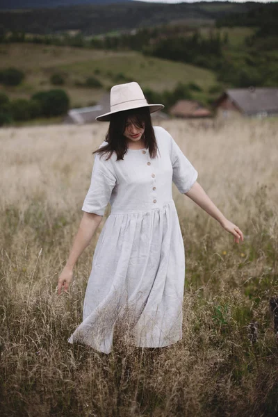 Stylish girl in linen dress and hat walking among herbs and wild — Stock Photo, Image