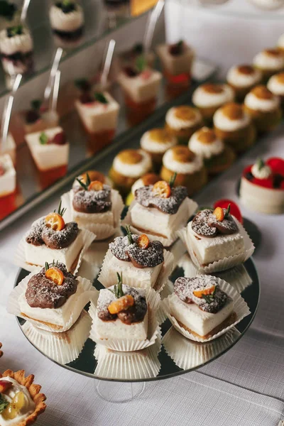 Sobremesas brancas e de chocolate com frutas e creme, cupcakes em — Fotografia de Stock