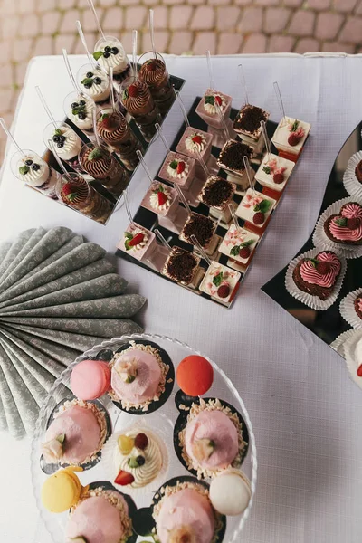Makanan penutup putih dan merah muda dengan buah-buahan dan krem, cupcakes pada berdiri — Stok Foto