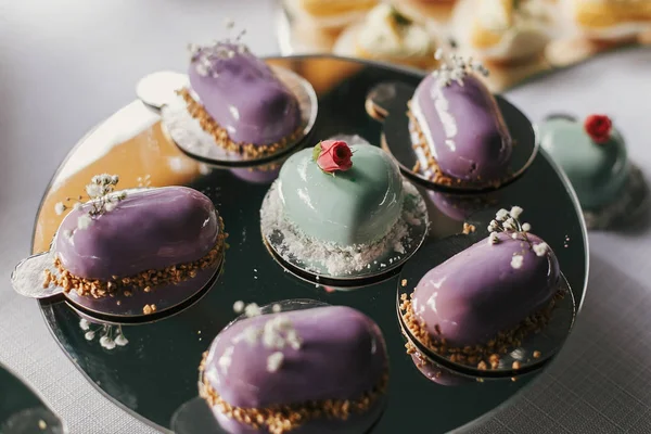 Eclares coloridos, sobremesas de creme de forma de coração em stand, moderno sw — Fotografia de Stock