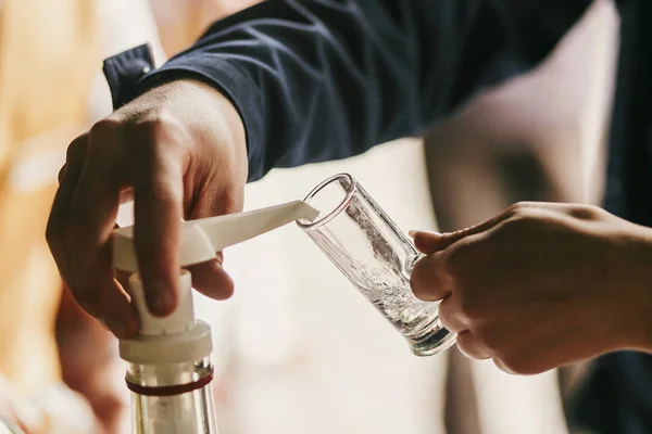 Garçom derramando vodka em vidro na mesa na recepção do casamento. Gue... — Fotografia de Stock