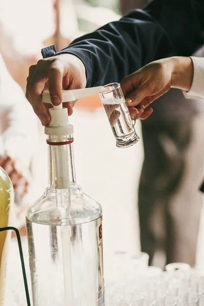 Kellner gießt Wodka in Glas auf den Tisch beim Hochzeitsempfang. Das Problem ist nur, dass wir nicht wissen, was wir tun. — Stockfoto