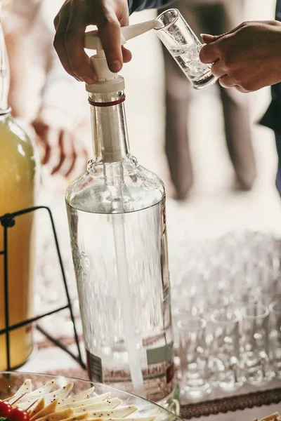 Kellner gießt Wodka in Glas auf den Tisch beim Hochzeitsempfang. Das Problem ist nur, dass wir nicht wissen, was wir tun. — Stockfoto