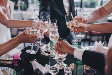 Bir grup insan şampanya kadehi tutuyor ve Weddin'e kadeh kaldırıyor.