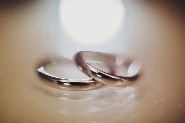 Elegantes anillos de boda de plata en la mesa, imagen macro borrosa con — Foto de Stock