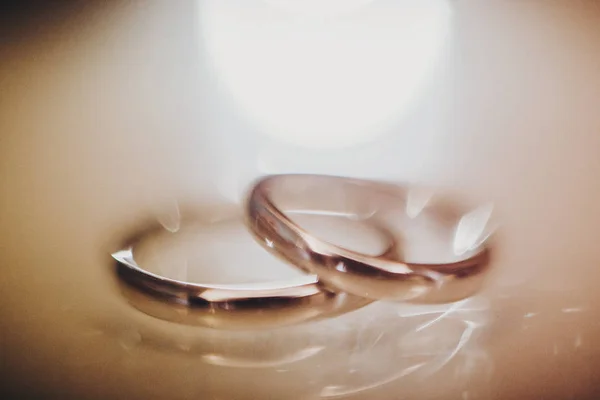 Stylish silver wedding rings on table, macro blurred image with — Stock Photo, Image