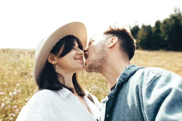 幸せなヒップスターのカップルは、自分撮りを作り、日当たりの良い山でキス — ストック写真