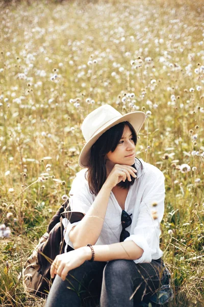 Hipster girl with backpack relaxing in wildflower meadow, travel — Stock Photo, Image