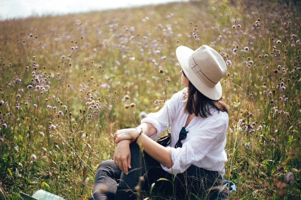 Sırt çantası ile Hipster kız kır çiçeği çayır, seyahat rahatlatıcı — Stok fotoğraf