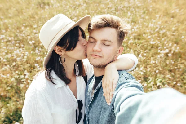 Feliz hipster casal fazendo selfie e beijos na ensolarada montanha — Fotografia de Stock
