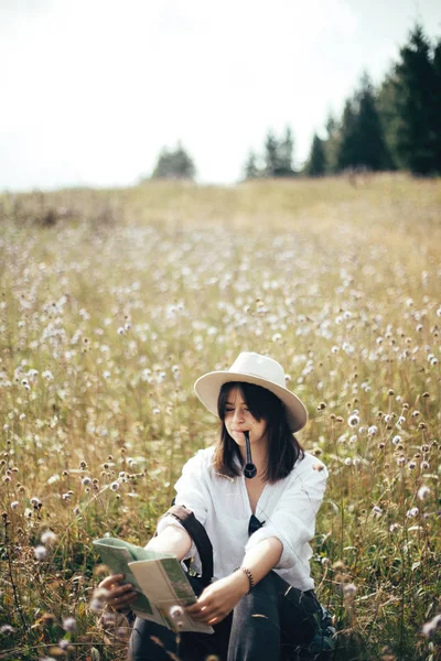 Hipster-Mädchen mit Holzpfeife schaut auf Landkarte und sitzt in der Sonne — Stockfoto