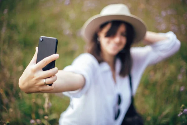 Hipster girl with backpack taking selfie on phone while relaxing — Stock Photo, Image