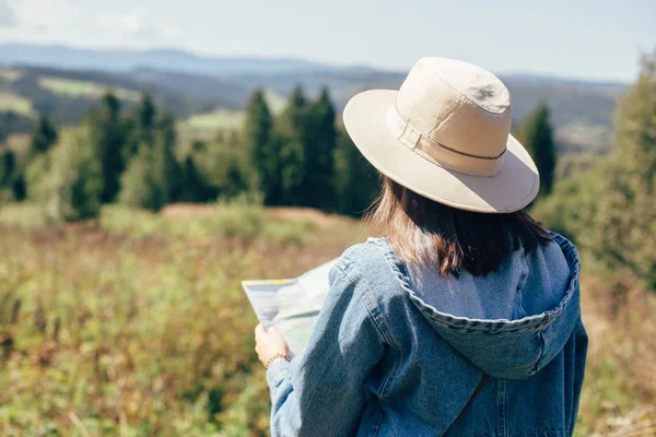 Stylish hipster girl holding map and traveling in sunny mountain — Stock Photo, Image