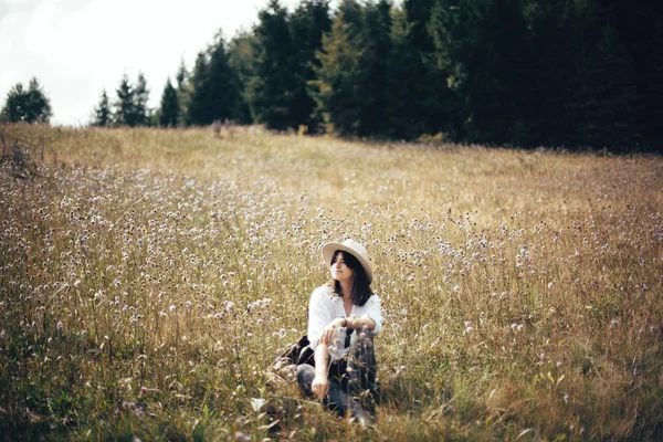 Ragazza hipster con zaino rilassante nel prato di fiori selvatici, viaggi — Foto Stock