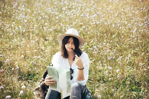 Hipster girl with wooden pipe looking at map and sitting in sunn — Stock Photo, Image