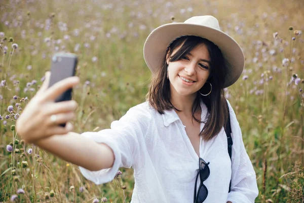 Хипстерская девушка с рюкзаком делает селфи по телефону во время отдыха — стоковое фото