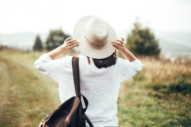 Sırt çantası ile Hipster kız seyahat ve s üstüne şapka tutarak