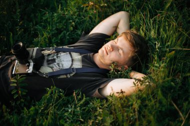 Yeşil çimenler içinde yatan film fotoğraf kamera ile şık hipster adam 