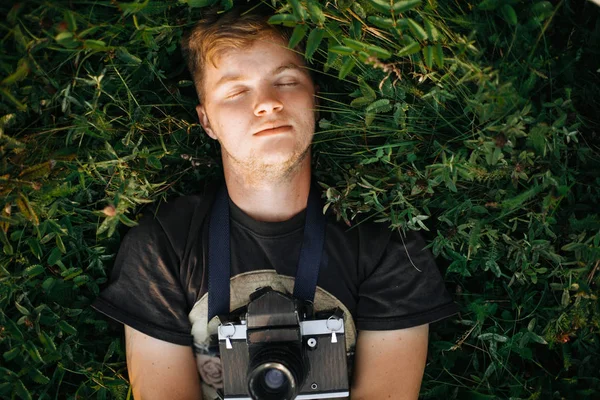 Stílusos csípő ember film fotó kamera fekvő zöld fű — Stock Fotó
