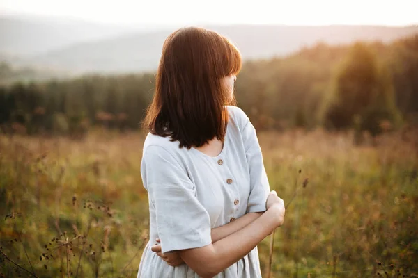 Stylish boho girl walking in grass and wildflowers in sunny mead — Stock Photo, Image