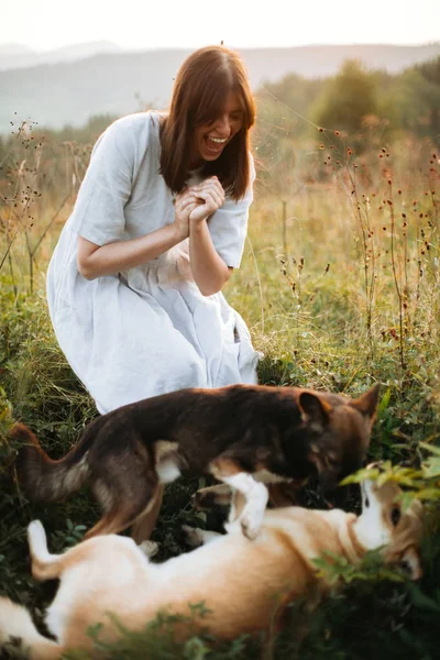 สไตล์ boho ผู้หญิงเล่นกับสุนัขน่ารักของเธอในหญ้าและ Wildfl — ภาพถ่ายสต็อก