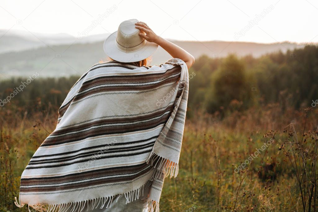 Stylish boho girl walking in sunny light at atmospheric sunset i