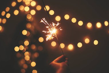Yeni Yılınız Kutlu Olsun. Altın arka planda elinde parlayan ışıltı