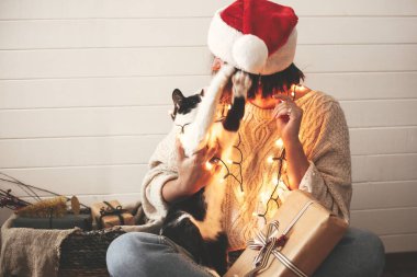Sevimli kedi şenlikli şık mutlu kız santa şapka ile oynuyor